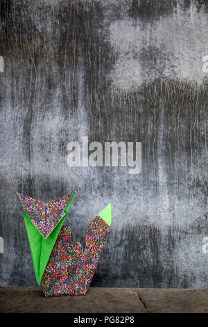 Origami fox in front of concrete wall Stock Photo