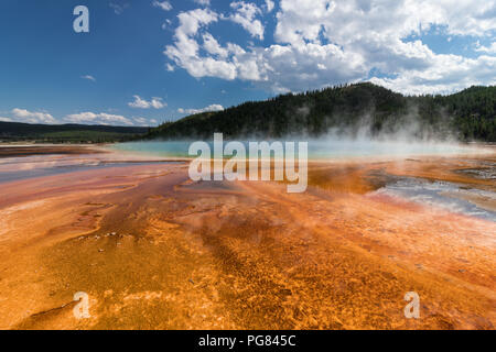 Grand Prismatic Spring - Yellowstone Park. Landscape on a Summer sunny day with clouds. Contrast of colors - Orange, Green Blue Stock Photo