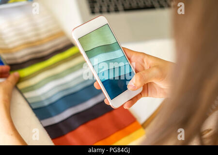 Fashion designer taking pictures of fabric samples with ger mobile phone Stock Photo