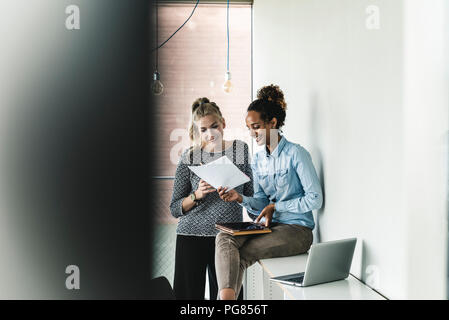 Young women working together in office, reading documents Stock Photo