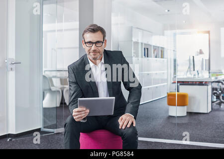 Portrait of confident businessman using tablet in office Stock Photo