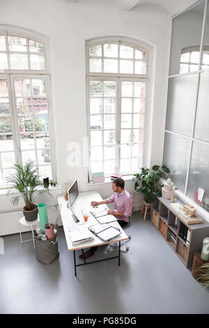 Man working at desk in a loft office Stock Photo
