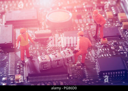 Ethereum ETH Cryptocurrency mining concept. Miniature virtual miner engineer working on the motherboard for mining the Ethereum cryptocurrency. Stock Photo
