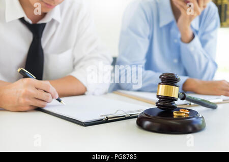 Angry couple arguing telling their problems to Judge gavel deciding on marriage to conclude an agreement on the divorce. They quarrel and argue with e Stock Photo