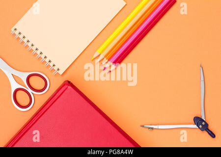 Book, scissors, notebook, color pencils and compass on pink background. Top view. Back to school concept. School supplies. Pastel colors Stock Photo