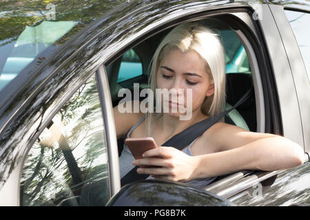 Distracted driver reading phone message, driving a car Stock Photo