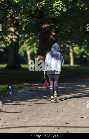 Northampton. U.K. 24th August 2018. A female taking her dog for a morning walk in Abington Park, temperatures were in single figures last night making it feel much colder this morning . Credit: Keith J Smith./Alamy Live News Stock Photo