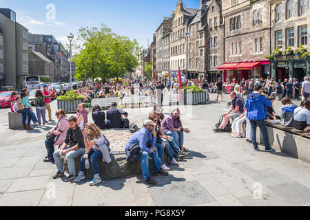 Tourists and locals relax and enjoy the sunshine in Edinburgh's Grassmarket. Stock Photo