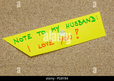 Note to my husband: I love you message written on yellow paper and pinned to cork bulletin board. Stock Photo