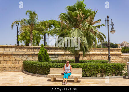 Caucasian lady on Holiday sitting on a park bench in Spain Stock Photo