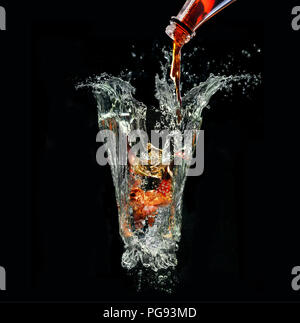 Imaginary picture with Cola drink being poured into metaphorical glass out of water splashes on black background Stock Photo