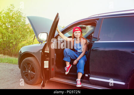 Wait for help on the road. Portrait of a young woman sitting in her car in working uniform. Stock Photo