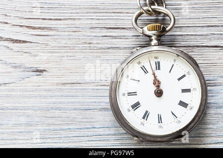 two minutes to twelve o'clock on retro pocket watch on gray wooden background Stock Photo