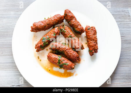 Indian cuisine - Mutton Seekh Kabab (Hyderabadi Seekh) from minced lamb meat roasted on skewers in tandoor on white plate on wood table Stock Photo