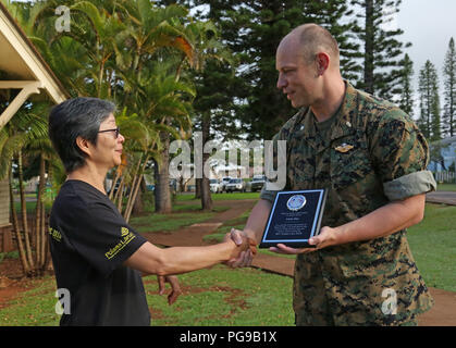 Linda Mau, Tropic Care volunteer and Lanai public health nurse, receives an appreciation plaque from U.S. Navy Cmdr. Jason Allen, Lanai site officer in charge, assigned to the 4th Dental Battalion Marine Forces Reserve, Atlanta, Ga. Aug. 19, 2018 at Lanai City, HI. Tropic Care Maui County 2018 is a joint-service, “hands-on” readiness training mission offering no cost medical, dental, and vision services to people at six locations across Maui, Molokai and Lanai from August 11-19. (U.S. Air National Guard photo by Airman First Class Mckenzie Airhart) Stock Photo