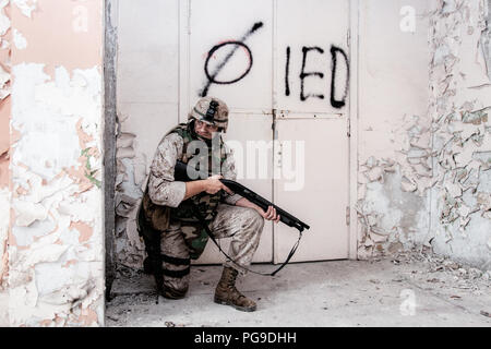 Marine shooter with shotgun take cover behind wall Stock Photo