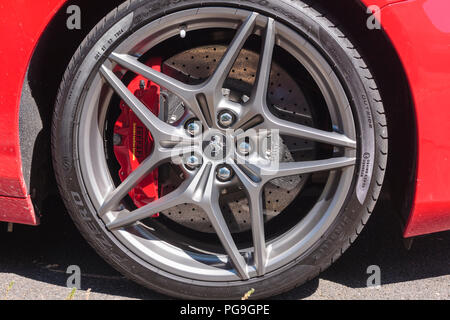 An alloy wheel of a Ferrari sports car, clearly showing the brake disc and red caliper Stock Photo