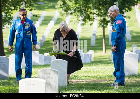 NASA astronaut Joe Acaba, left, and Mark Vande Hei, right, watch as Julie Vande Hei, wife of Mark, places a flower at the gravesite of former astronaut and U.S. Senator John Glenn, Friday, June 15, 2018 at the Arlington National Cemetery in Arlington, Va. Stock Photo