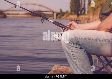 Fishing on the lake. Fisherman holding fishing rod with reel Stock Photo