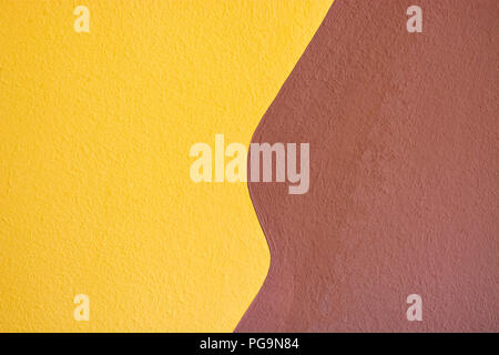 A fragment of a wall plastered in two colors, yellow and brown, for use as a background. Stock Photo