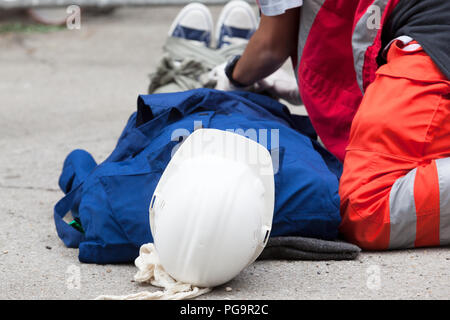 Paramedics helping a worker after the fall at a construction site. First aid training. Stock Photo
