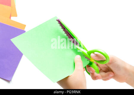 Children's hands cut out colored paper with figured scissors. Activities for children, leisure Stock Photo