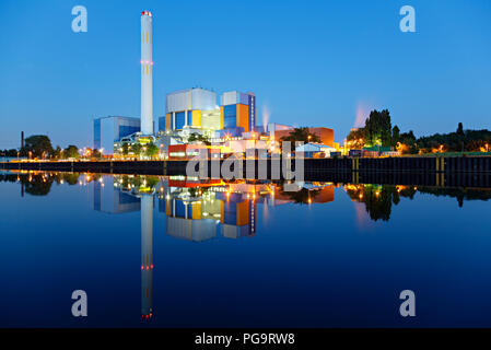 An incineration plant at a canal at blue hour in the night. Strong colors and very clear reflection. Stock Photo