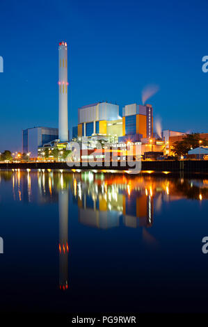 An incineration plant at a canal at blue hour in the night. Strong colors and clear reflection. Stock Photo
