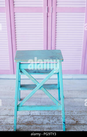 Turquoise stepladder on a pink background of doors blinds.Combination of color Stock Photo