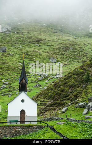 Secluded chapel on a misty day on top of a mountain in Switzerland. Stock Photo