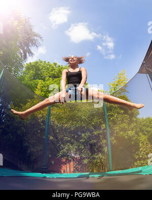 Girl gymnast jumping on trampoline, doing splits Stock Photo