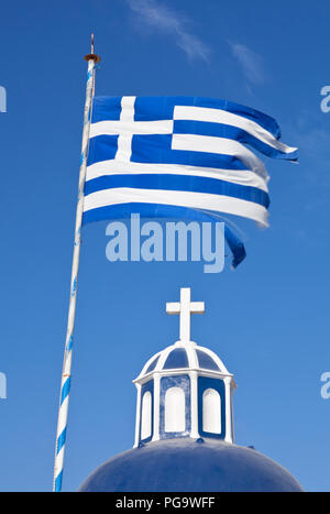 A blue and white church top with cross and an equally colored greek flag with blue sky. Stock Photo