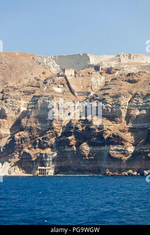 View from a boat to the southeastern crater wall of Santorini, Greece with some old industrial buildings for pumice export down at the coast. Stock Photo