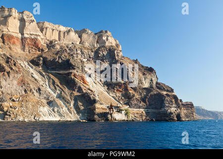 View from a boat to the southeastern crater wall of Santorini, Greece with some old industrial buildings for pumice export down at the coast. Stock Photo