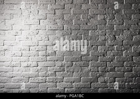 Part of a brick stone wall with illumination. Surface of the brick wall which is brightly illuminated on the one hand. The image is black-and-white. Stock Photo