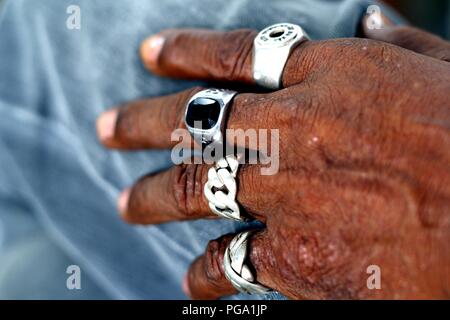 Close up photo of a hand of an old man with rings on each finger. Stock Photo