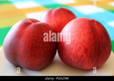 Close Up of Three Fresh Ripe Plum Fruits Served on White Plate Stock Photo