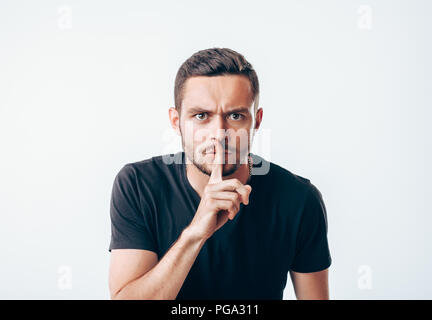 Young man holding index finger on lips asking for silence.  Secret concept Stock Photo