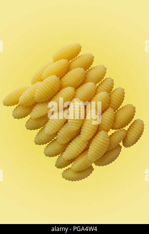 pasta dumplungs of durum wheat semolina also called malloreddus or gnocchetti sardi , Italian pasta , studio shot , yellow  background Stock Photo