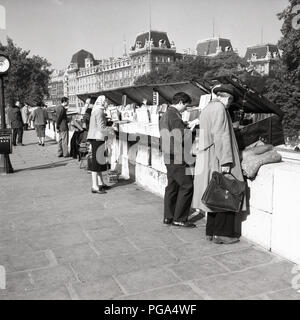 1950s, historical, people looking through the 'book boxes' of the 'Les Bouquinistes', the small book sellers of used and antiquarian books on the riverside of the Seine, Paris, France. Stock Photo