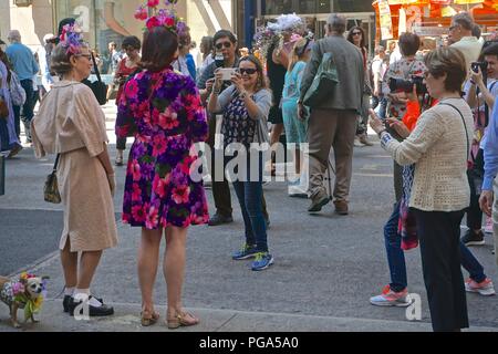 Tourists take photos of two women wearing colorful Easter bonnets as their dog stands by patiently, at the annual Fifth Avenue Easter Parade. Stock Photo