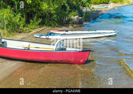 Group of canoes and kayaks on a lake shore in park, Canada. Stock Photo