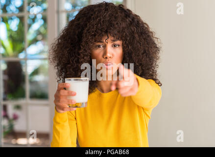 African american woman holding a glass of milk pointing with finger to the camera and to you, hand sign, positive and confident gesture from the front Stock Photo