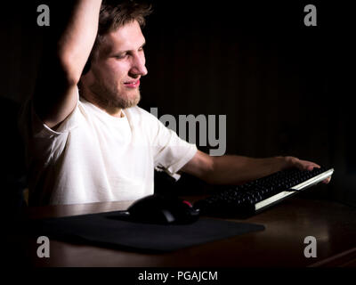 young mad crazy gamer breaking the keyboard playing video games on computer late in the night Stock Photo