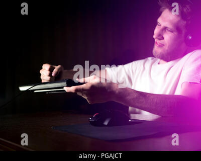 young mad crazy gamer breaking the keyboard playing video games on computer late in the night Stock Photo