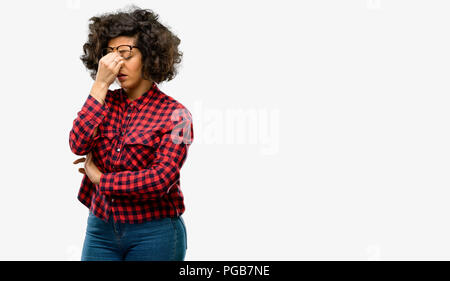 Beautiful arab woman with sleepy expression, being overworked and tired, rubbes nose because of weariness Stock Photo
