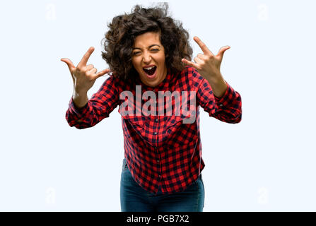 Beautiful arab woman making rock symbol with hands, shouting and celebrating Stock Photo