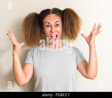 Brazilian woman wearing pigtails very happy and excited, winner expression celebrating victory screaming with big smile and raised hands Stock Photo