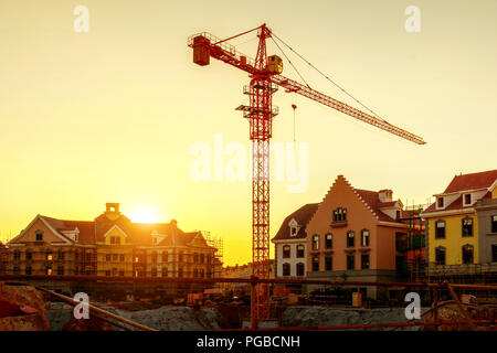 Construction site, silhouettes of construction industry workers on scaffolding against the sunset light. Stock Photo