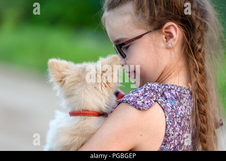 A girl with a little dog on her shoulder, rear view Stock Photo